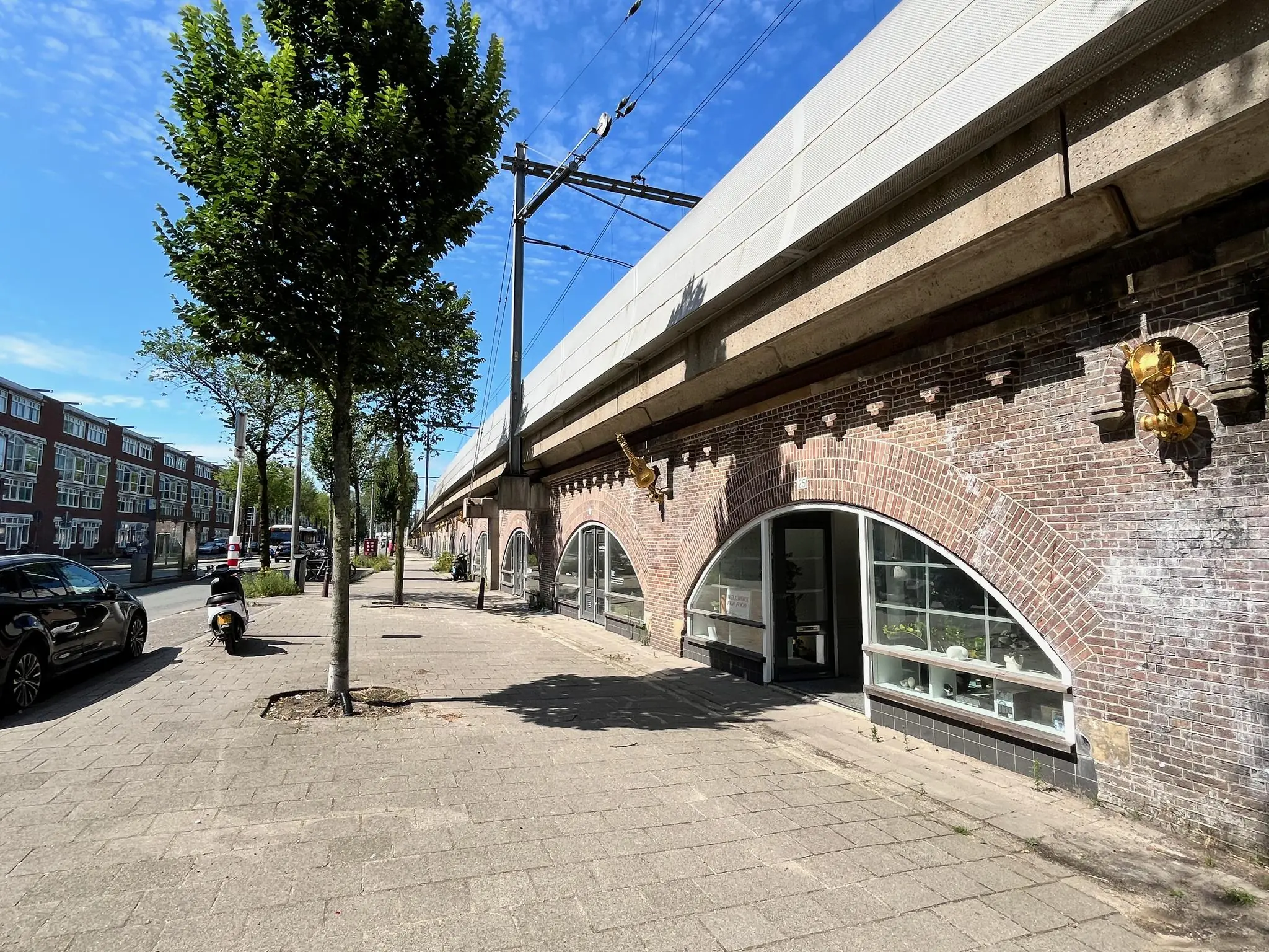 Gezicht op de winkelruimtes in de bogen onder het spoorviaduct bij ‘Tussen de Bogen’ in Amsterdam op een zonnige dag.